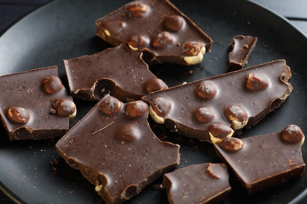 Foto chocolade met noten op zwart donkere chocoladestukjes close-up