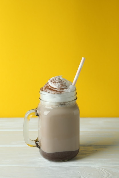 Chocolade milkshake op houten tafel tegen gele achtergrond