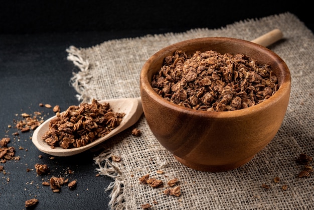 Chocolade muesli in houten kom op zwarte achtergrond.