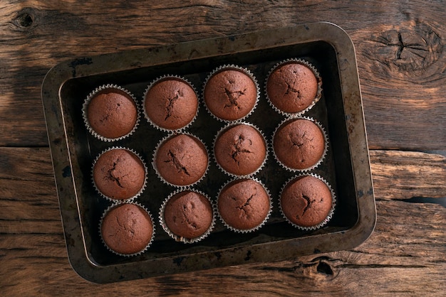 Chocolade muffins in bakplaat op houten tafel bovenaanzicht Zelfgemaakte bakkerij Donkere achtergrond