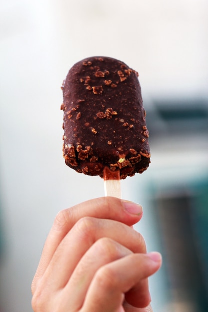 Chocolade ondergedompeld ijslollyijs bij de hand