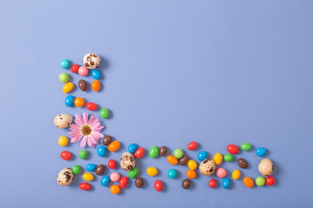 Foto chocolade paaseieren en bloemen op blauw papier achtergrond