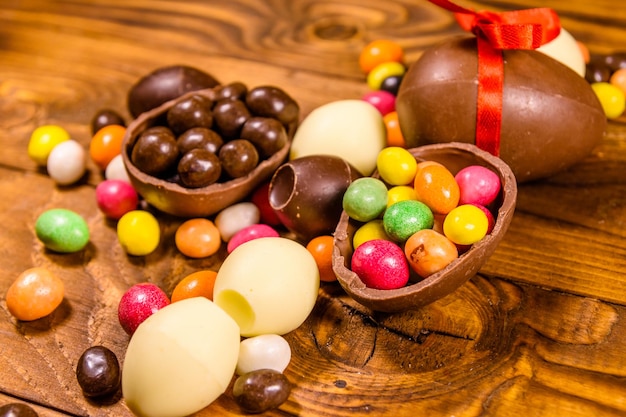 Foto chocolade paaseieren en veelkleurige snoepjes op een houten tafel