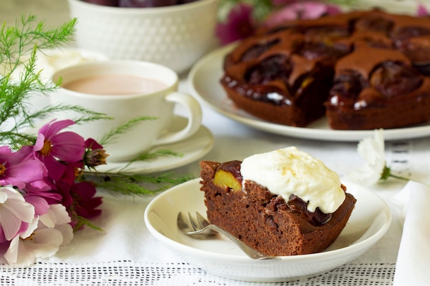 Chocolade pruimentaart met slagroom, geserveerd met cacao. Rustieke stijl.