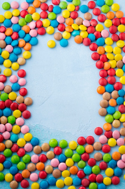 Chocolade ronde snoep in een veelkleurige suikerglazuur op lichtblauwe tafel. Selectieve aandacht. Bovenaanzicht. Plaats voor tekst.