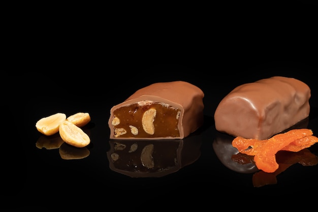 Chocolade snoepjes op een donkere ondergrond met reflectie. Vullen van noten en fruit. Ruimte kopiëren.