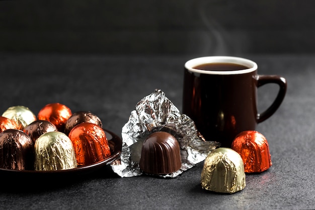 Chocolade snoepjes verpakt in veelkleurige folie en twee kopjes koffie