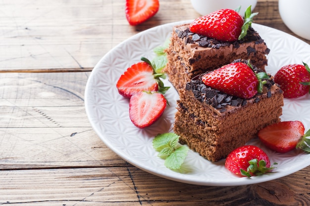 Chocolade truffeltaart met aardbeien en munt. Houten tafel. Ruimte kopiëren