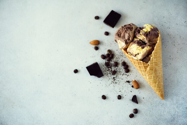 Chocolade, vanille en koffie-ijs in wafel kegel met koffiebonen op grijze steen. Zomer eten concept, kopie ruimte. Gezond glutenvrij ijs