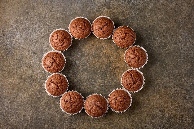 Chocolade zelfgemaakte cupcakes opgemaakt in de vorm van een cirkel op een houten oppervlak, kopie ruimte, boven