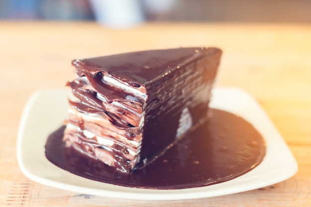 Chocoladecake op witte schotel en houten lijst in koffiewinkel