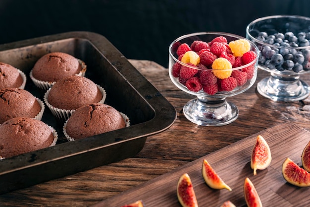 Chocoladecakes in bakpan en verse seizoensbessen op houten tafel Zelfgemaakte muffins