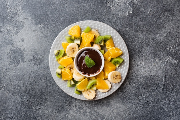 Chocoladefondue met fruit op een donker beton