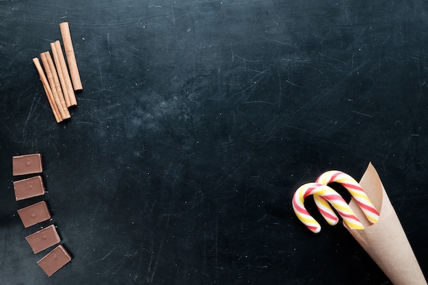 Chocoladekaneel en suikergoed vlakke mening zwarte achtergrondexemplaarruimte