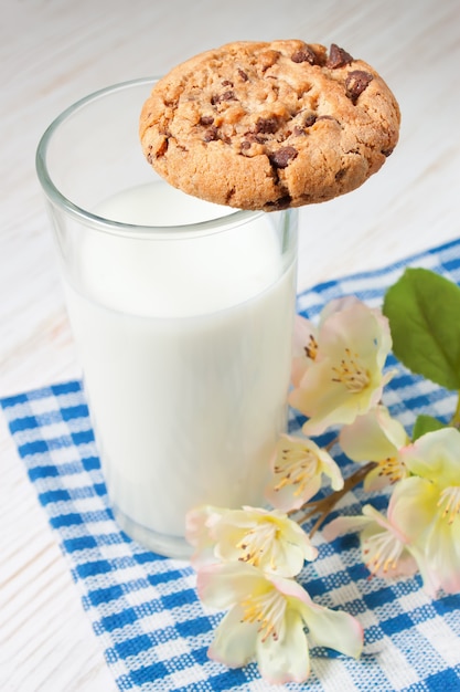 Chocoladekoekje en glas melk op servet op witte houten lijst