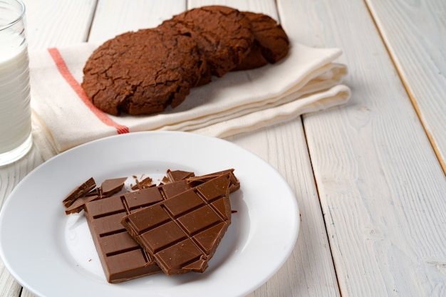 Chocoladekoekjes en chocoladereep op witte houten raad