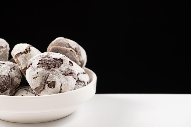 Chocoladekoekjes met cacao en suikerpoeder op een bord op een zwarte achtergrond