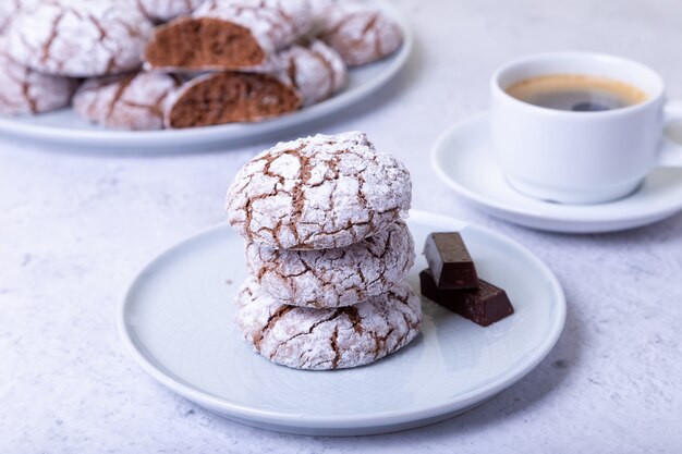 Chocoladekoekjes met scheuren, bezaaid met poedersuiker en een kopje koffie