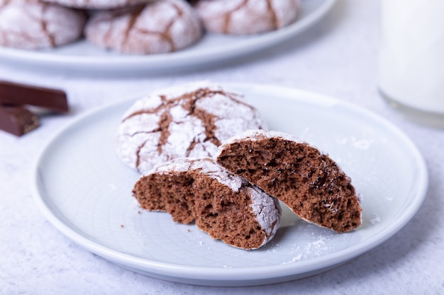 Chocoladekoekjes met scheuren, bezaaid met poedersuiker en een mok melk