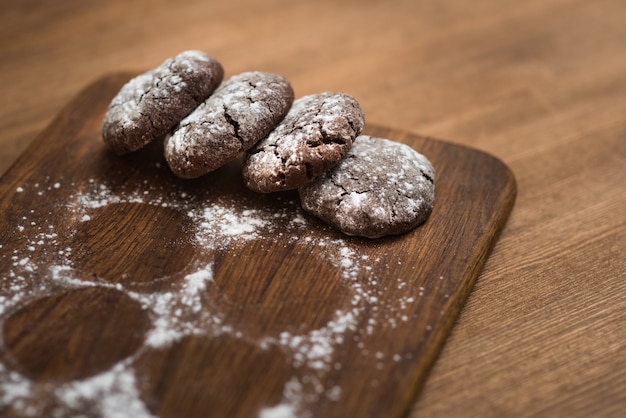 Chocoladekoekjes met suikerpoeder op houten keukenbord