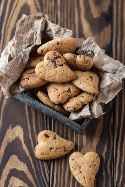 Chocoladekoekjes op houten rustieke lijst. Chocoladeschilferkoekjes in de vorm van een hart. Zelfgemaakte Koekjes