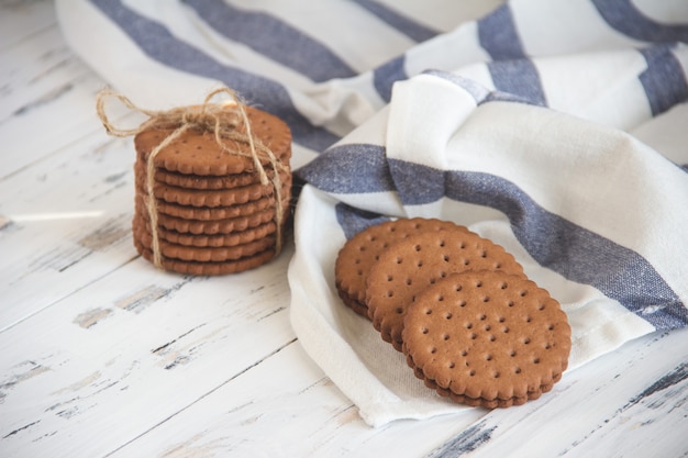 Chocoladekoekjes op licht servet op witte houten lijst.