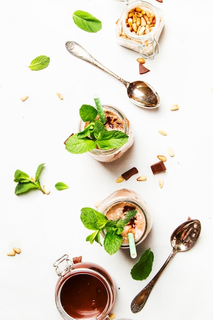 Chocolademilkshake of melkcocktail met topping van groene munt en cedernoten, witte keukentafel, kopieerruimte bovenaanzicht