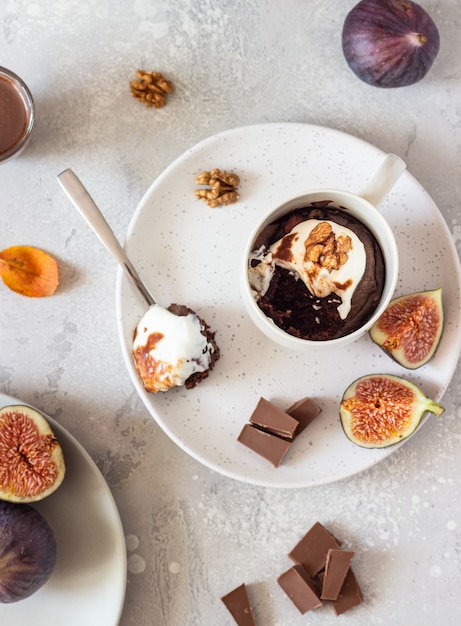 Chocolademok cupcake met roomkaas of ricotta met karamelsaus in een witte keramische mok. Comfort herfst- of wintervoedsel.