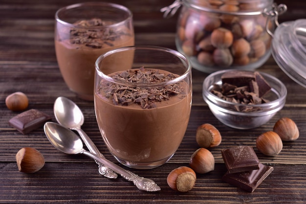 Chocolademousse met hazelnoten in glazen op een donkere houten achtergrond.