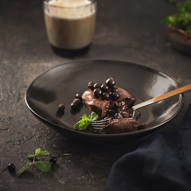 Chocolademuffin met bosbessen in zwarte plaat op donkere achtergrond met koffie