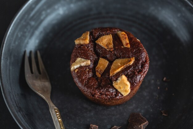 Chocolademuffin met stukjes banaan op donkere plaat met vork