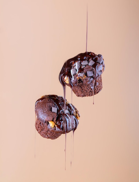 Chocolademuffins bedekt met chocoladesuikerglazuur in levitatie op een warme beige achtergrond