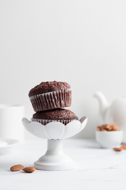 Chocolademuffins in een witte taartstandaard op een witte tafel