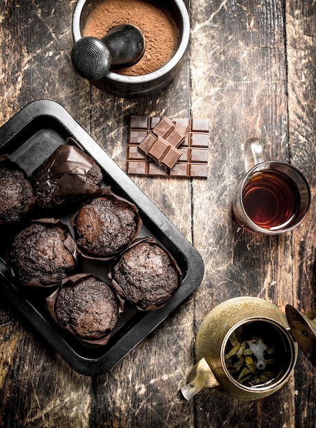 Chocolademuffins met geurige thee op houten tafel.