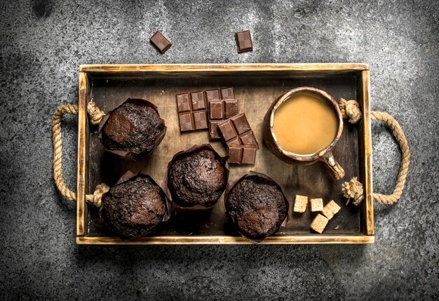 Chocolademuffins met koffie. Op een rustieke tafel.