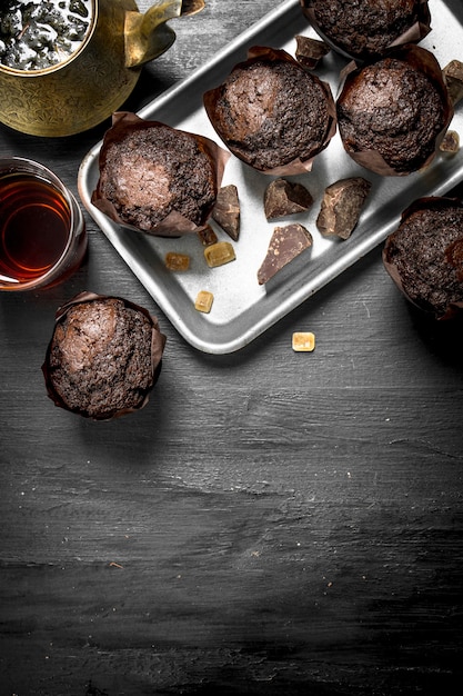 Chocolademuffins met verse thee op zwart bord.