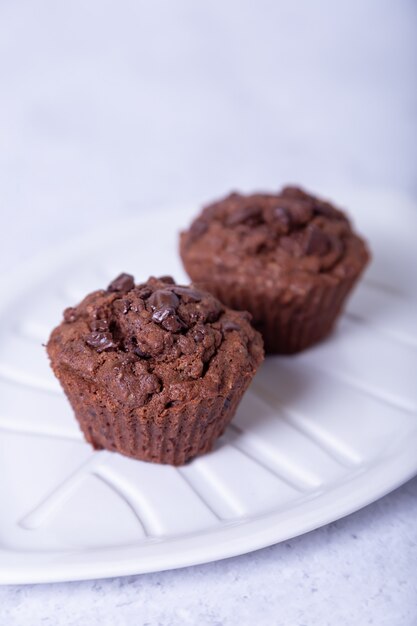 Chocolademuffins op een witte plaat. Zelfgemaakt bakken. Witte achtergrond. Selectieve aandacht, close-up.