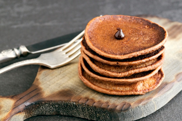 Chocoladepannekoeken met chocoladesaus op een donkere achtergrond.