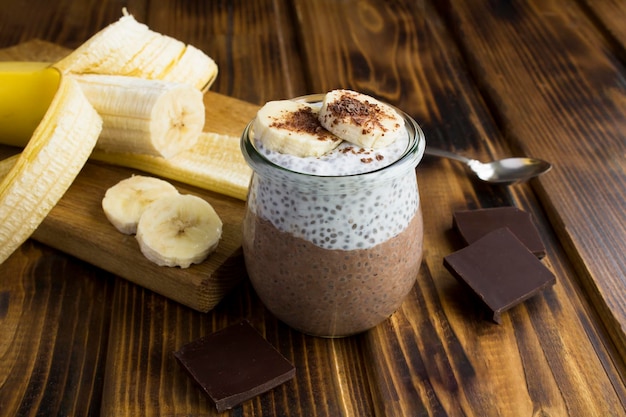 Chocoladepudding met chiazaad en banaan in de glazen pot op de houten achtergrond