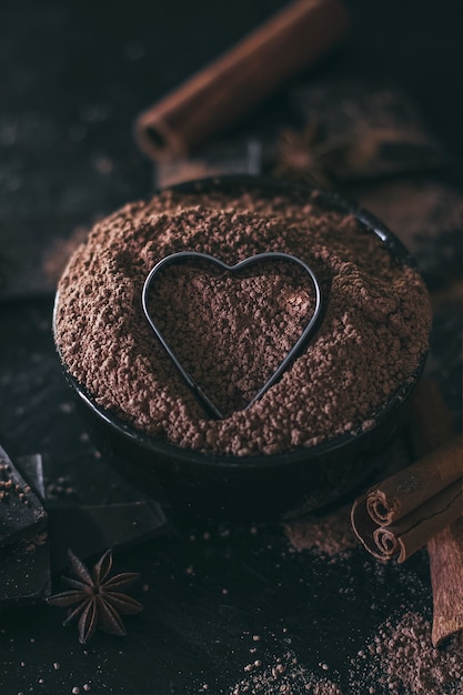 Chocoladereepstukken met cacaopoeder en hartvorm op donker