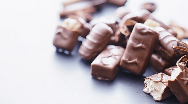 Foto chocoladerepen op een zwarte achtergrond in tegenlicht. chocolade met vulling. zoete snoepjes voor snack en thee.