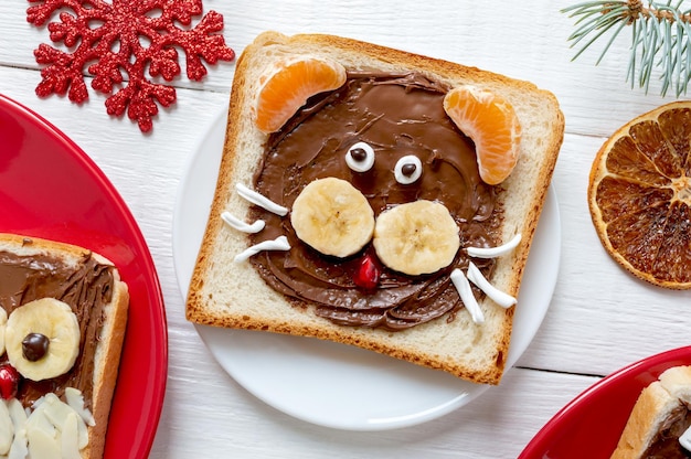 Chocoladesandwich in de vorm van een tijger - eetbaar symbool van het jaar 2022. Kerstontbijt met banaan en mandarijn voor kinderen. Bovenaanzicht