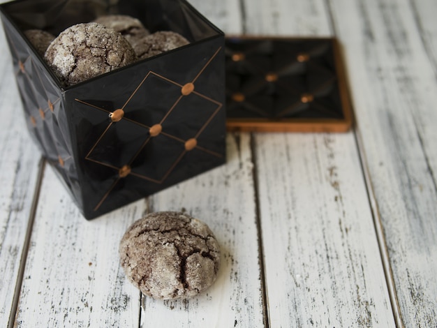 Chocoladeschilferkoekjes met barsten, Zwarte uitstekende doos met koekjes op witte achtergrond.
