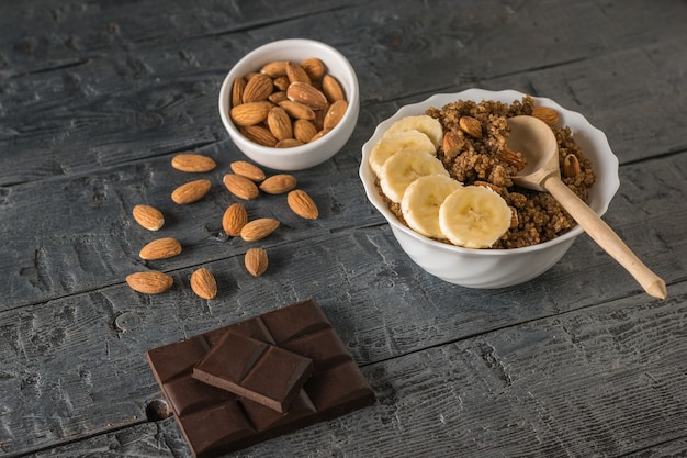 Chocoladeschilfers, amandelen en quinoapap met banaan op een houten lijst. Gezond dieet.