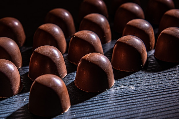 Chocoladesnoepjes gevuld met aardbeiensaus koeling op een zwart houten aanrecht