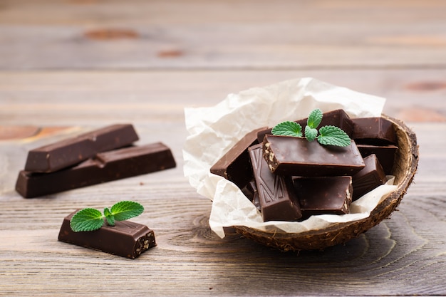 Chocoladestukjes en muntblaadjes in een kom en op een houten tafel. Het concept van overgewicht door snoep