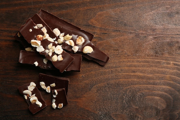 Chocoladestukjes met noten op een houten achtergrond kleur