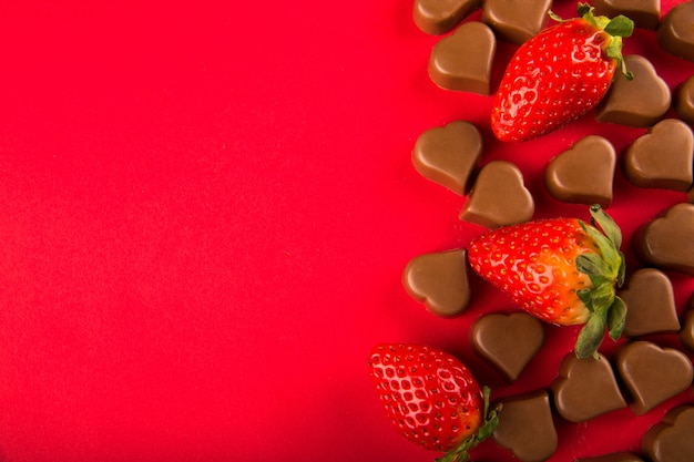 Chocoladesuikergoed en aardbeien op rode achtergrond, de Dag van Valentine