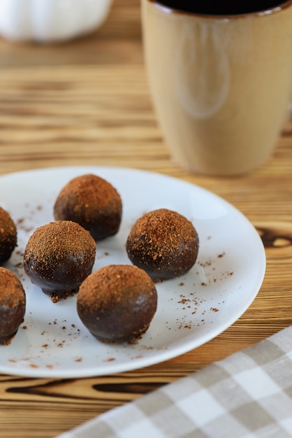 Chocoladesuikergoed met een kop van koffie op een houten lijst.