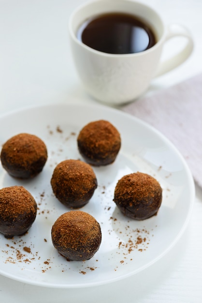 Chocoladesuikergoed met een kop van koffie op een witte lijst.